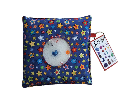 Close-up of a Seek & Find game filled with colorful trinkets and Victory Pellets, showing smooth plastic beads surrounding tiny treasures in a clear sensory pouch.